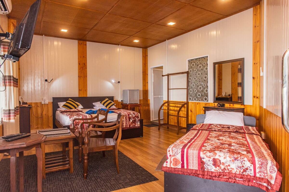 A room with two beds, a desk, a chair, a television, and a mirror.