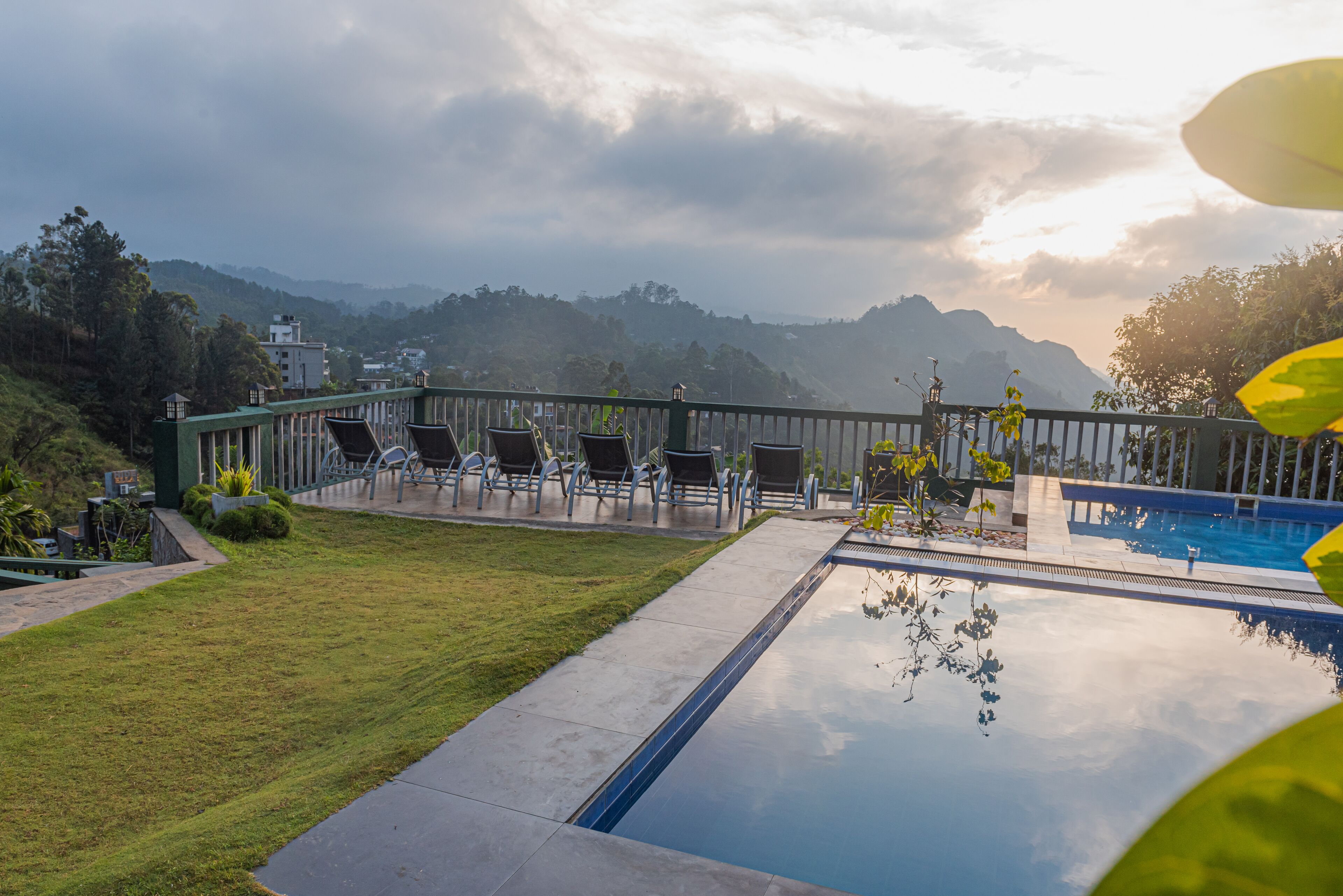 Zona de piscina con vistas a montañas, mobiliario exterior y césped cuidado.