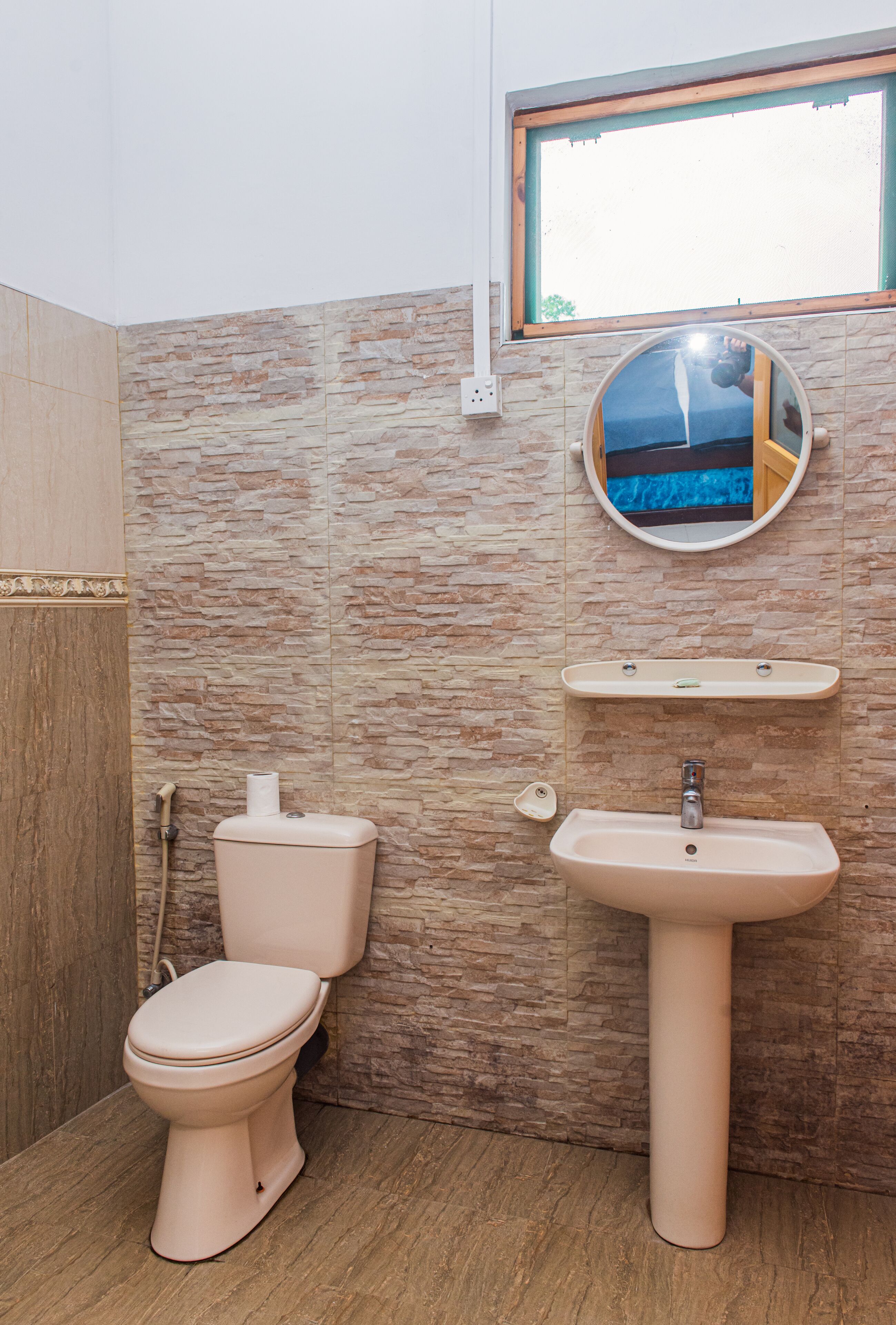 A bathroom with a toilet, sink, and a mirror.