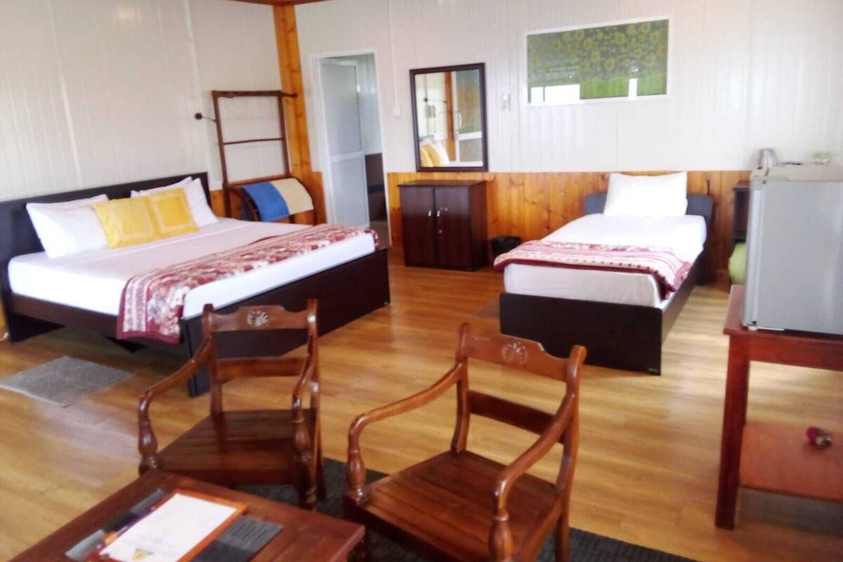 A hotel room with two beds, a desk, a chair, a dresser, and a mirror.
