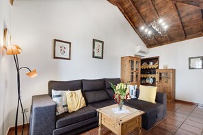 Una sala de estar con un sofá, una mesa de centro de madera, una lámpara de pie y una araña.