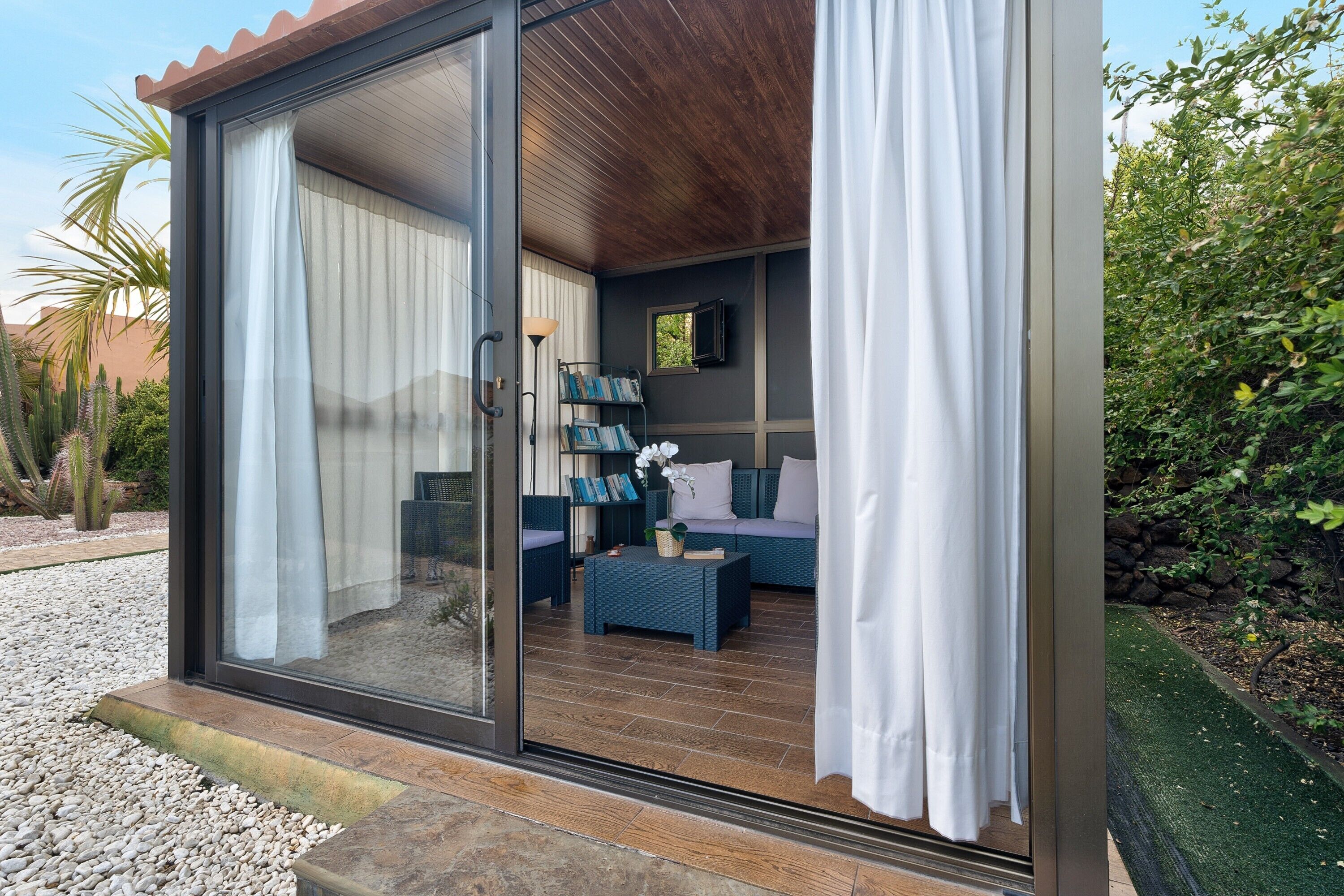 A modern interior with a sliding glass door, a sofa set, a bookshelf, and a small table.