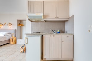 A compact kitchen with a built-in stove, a small sink, and light-colored cabinets.