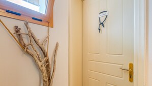 Una porta bianca con maniglia in ottone e una corda legata a una targhetta con la scritta 'PAXOS'.