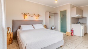 Una camera da letto con un letto, comodini, un armadio e un angolo cottura. Include un bagno con porta in vetro.