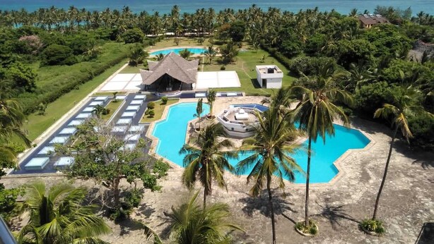 Un complexe hôtelier doté de plusieurs piscines, d’un grand bâtiment et d’une plage.