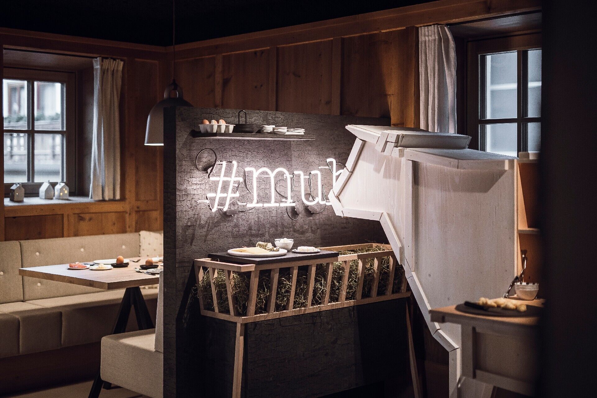 Une pièce chaleureuse aux murs en bois, une table avec une assiette de nourriture et un panneau lumineux au néon.