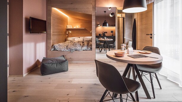 Ett modernt hotellrum med en säng, en matplats, en TV och ett stort fönster.