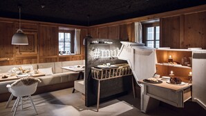 Una habitación acogedora con paredes de madera, chimenea de piedra, sofá, mesa de comedor y zona de bar.