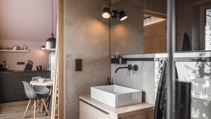 A modern bathroom with a large mirror, a white sink, and a towel rack. - Rousa Little Guesthouse Kombi – Breakfast Included! (Rasun Anterselva)