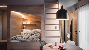 A modern bedroom with a loft bed, a dining area with a table and chairs, and a pendant light. - Rousa Little Guesthouse Kombi – Breakfast Included! (Rasun Anterselva)