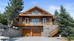 A two-story log cabin with a stone facade, wooden balconies, and a stone staircase leading to the upper level. - Amazing Grace - Fireplace, Jet Tub, Deck, Lake View (Fawnskin)
