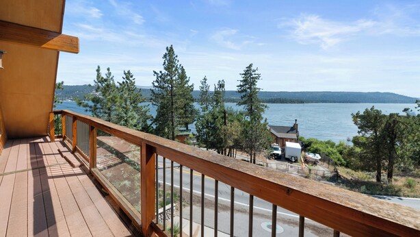 A wooden deck with a view of a lake, trees, and a distant shoreline. - Amazing Grace - Fireplace, Jet Tub, Deck, Lake View (Fawnskin)
