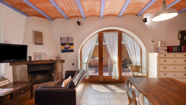 Ein Wohnzimmer mit Kamin, Fernseher, einer Couch und einem Essbereich mit Tisch und Stühlen.