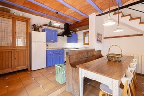 Una cocina con armarios de madera, un refrigerador blanco y una mesa de comedor de madera con sillas.