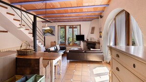Ein geräumiger Wohnbereich mit Holzboden, Kamin, Fernseher und einer Treppe, die eine weitere Ebene hinaufführt.