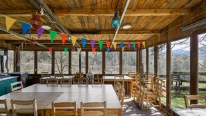 A rustic wooden dining area with large windows, wooden tables, and chairs.