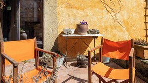 An outdoor seating area with orange chairs, a table with potted plants, and a building entrance with a sign reading 'ElReixac'. - Vacation Home "Els Mossos, El Reixac Casa Rural" with Mountain View, Shared Pool & Wi-Fi (Sant Joan de les Abadesses)