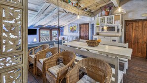A rustic interior with wicker furniture, a wooden ceiling, and a kitchen area with a wooden door. - Vacation Home "Els Mossos, El Reixac Casa Rural" with Mountain View, Shared Pool & Wi-Fi (Sant Joan de les Abadesses)