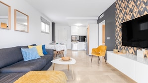 A modern living room with a sofa, a dining table, and a kitchen in the background. - Sungolfbeach El Girasol (orihuela)