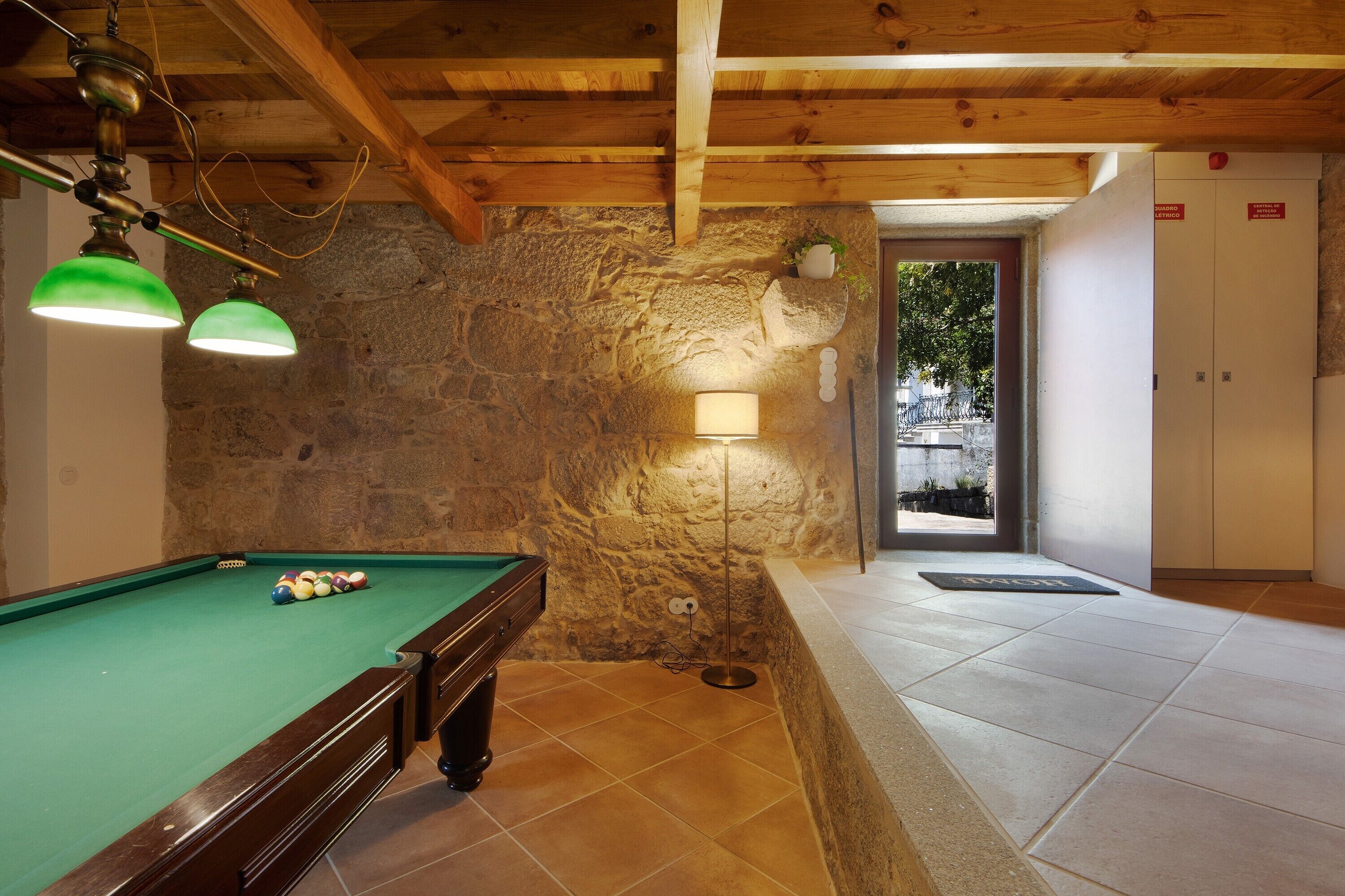 A pool table with balls, a lamp, and a stone wall.
