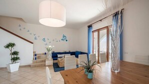 Una sala de estar moderna con una mesa de comedor de madera, sofá azul y adhesivos decorativos en la pared.