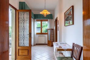 A hallway with a wooden door, a dining table with chairs, a hanging light fixture, and a window with curtains. - Family-Friendly Vacation Home "Casa Umbé" with Private Terrace & Wi-Fi (Pietrasanata)