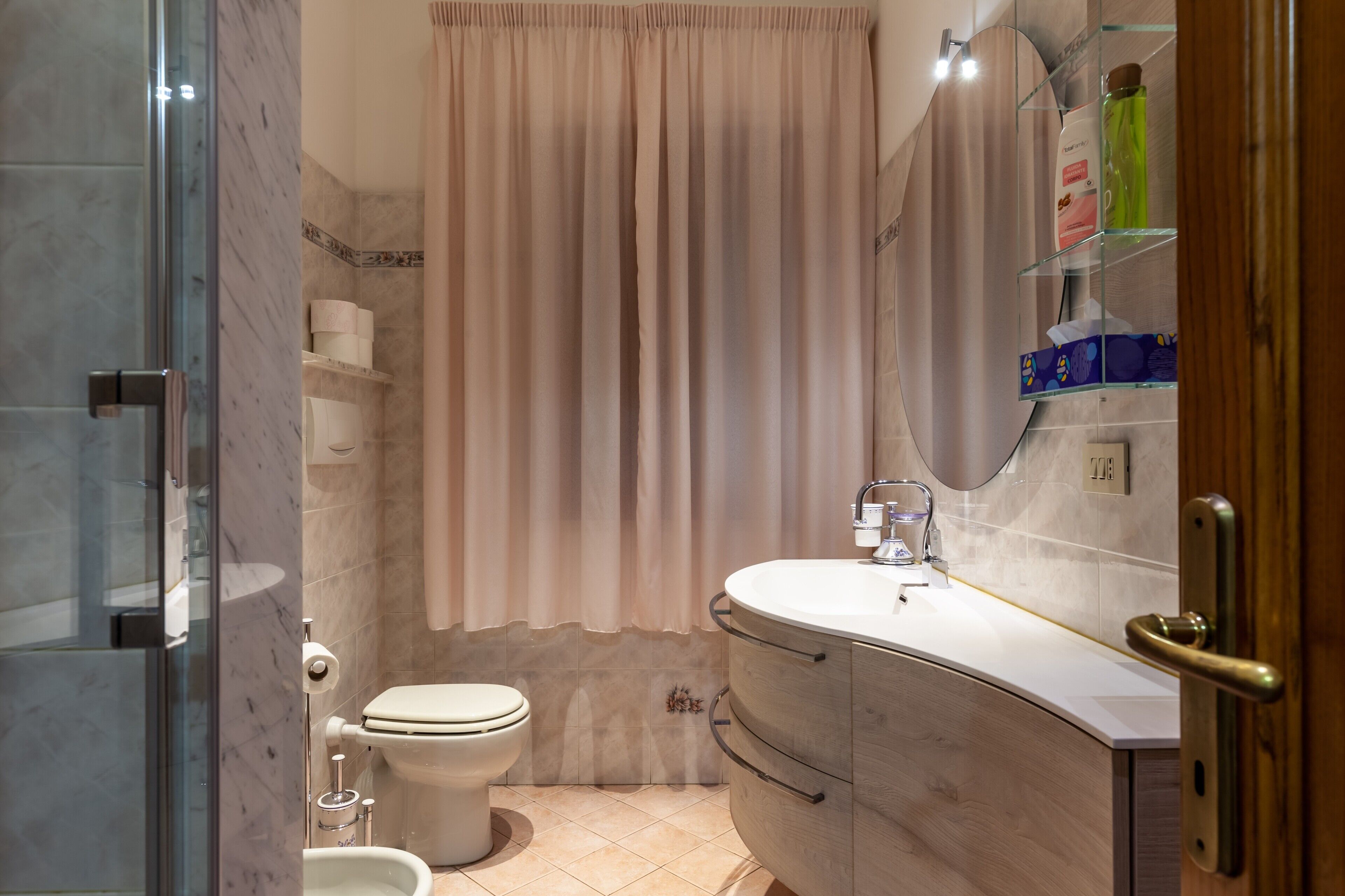 A bathroom with a toilet, shower, and vanity with a mirror.
