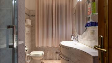 A bathroom with a toilet, shower, and vanity with a mirror.
