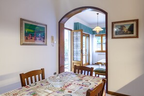 Un coin repas avec une table dressée pour deux personnes, un bol décoratif en verre et une nappe à motifs.