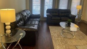 A living room with two black leather sofas, a glass coffee table, and a lamp on a side table. - Beautiful 2 Bedroom / 2 Bath Apartment in Houston by NRG Stadium (Houston)