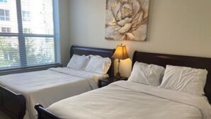 A hotel room with two beds, a nightstand with a lamp, and a large floral artwork on the wall. - Beautiful 2 Bedroom / 2 Bath Apartment in Houston by NRG Stadium (Houston)