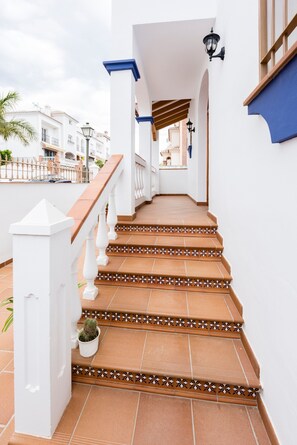 A staircase with white railings and terracotta tiles leading to a covered area with a lamp post. - Holiday Home 'Villa Zoe' with Sea View, Wi-Fi and Air Conditioning (Nerja)