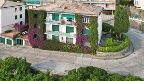 Ein mehrstöckiges Gebäude mit Balkon, grünen Fensterläden und einer Stein-Fassade.