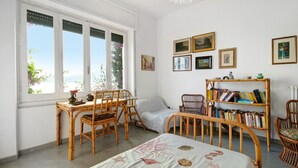 Ein Zimmer mit einem Bett, zwei Stühlen, einem Tisch, einem Bücherregal und einem Fenster mit Blick.
