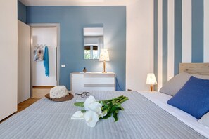 A bedroom with a bed, bedside table, lamp, and a mirror.