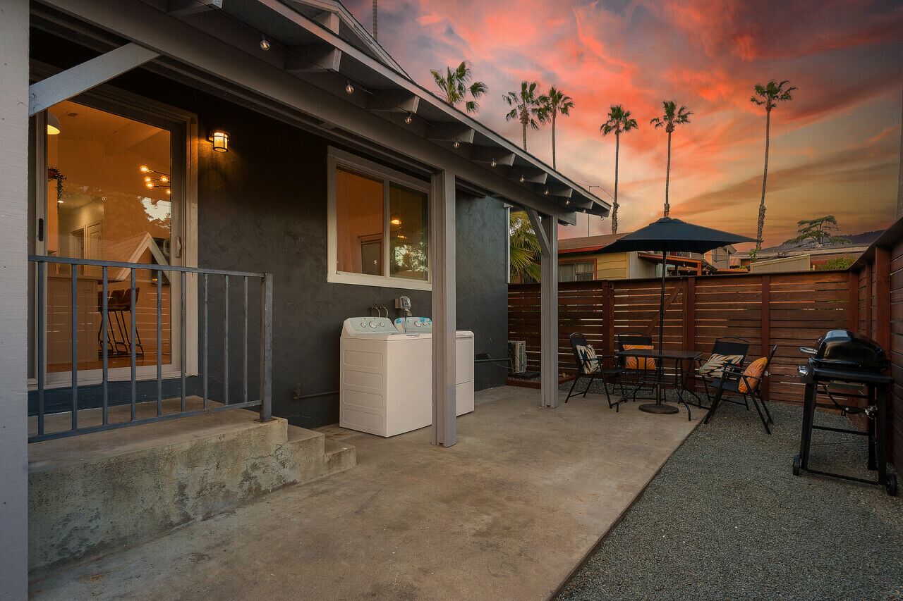 Propiedad residencial con patio cubierto, mobiliario exterior y lavadora.