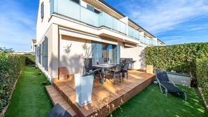 Una casa moderna a due piani con un patio, posti a sedere all'aperto e un prato curato.