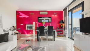 Un soggiorno moderno con zona pranzo, televisione e balcone dotato di barbecue.