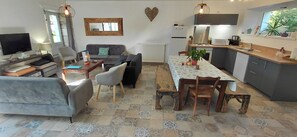 Une cuisine moderne avec un coin repas, un salon doté d’un canapé et d’une télévision, et un cœur décoratif accroché au mur.