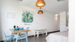 A room with a bed, a dining table with chairs, a bench, a wall-mounted artwork, and a ceiling light fixture. - Studio "Dannamar" near the beach with private terrace and Wi-Fi (Puerto del Carmen)
