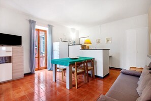 A compact living space with a dining area, kitchenette, and a sofa.