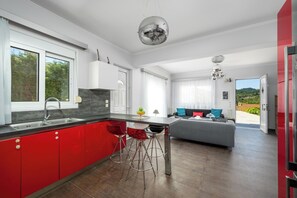Une cuisine moderne avec des meubles de couleur rouge, un îlot central et un coin repas comprenant un canapé et des chaises.