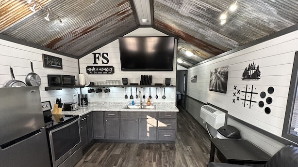 A modern kitchen with a large TV, stainless steel appliances, and a wooden floor. - FS Rental #3 Annapolis, MO Black River (Annapolis)