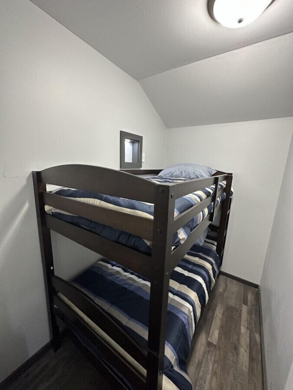 Een stapelbed in een kleine kamer met witte muren en een schuine plafond.