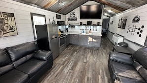A compact kitchen with a central island, black leather sofas, and a mounted TV. - FS Rental #3 Annapolis, MO Black River (Annapolis)