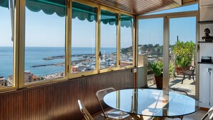 Un balcon avec une table et des chaises en verre, donnant sur une marina et une ville côtière.