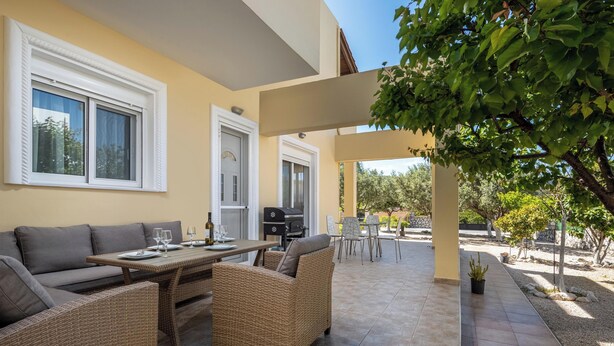 Un patio al aire libre con mobiliario de mimbre, una mesa de comedor y una parrilla.