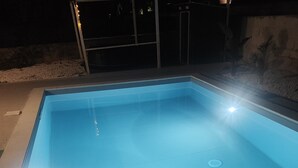 En rektangulär swimmingpool med trappsteg som leder ner i den, omgiven av en betongplatta.