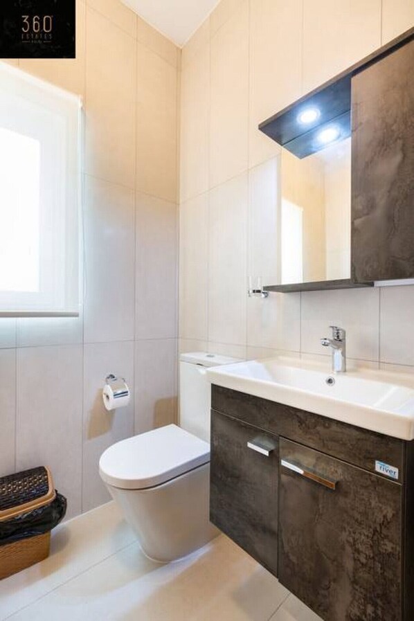 A modern bathroom with a toilet, sink, and mirror.